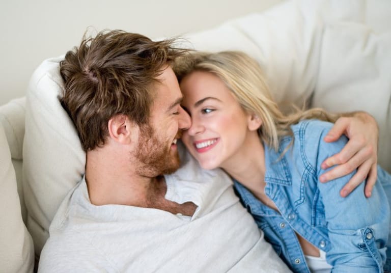 smiling couple being affectionate on couch