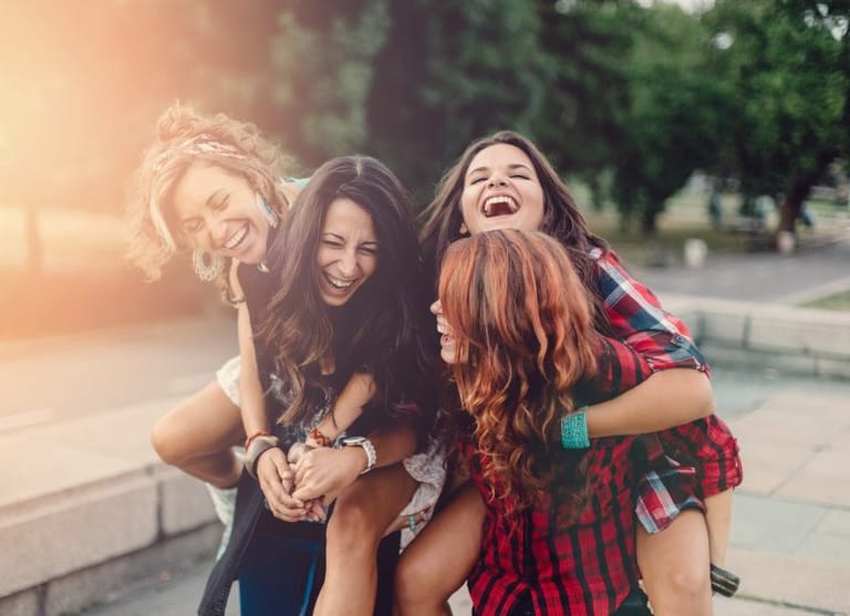 four female friends laughing outdoors