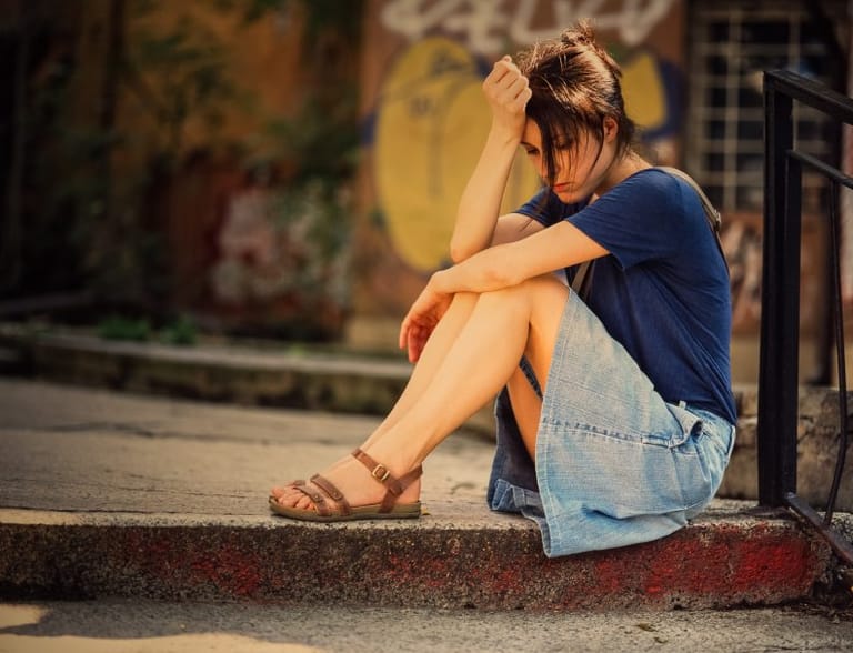 unhappy woman sitting on pavement
