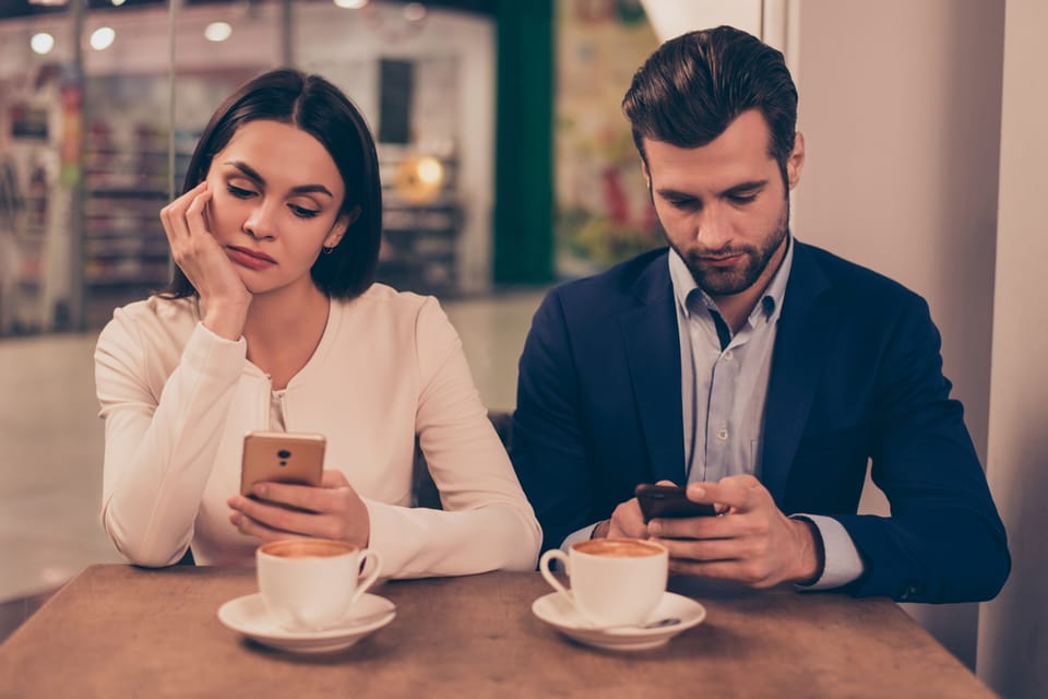 Couple in a cafe both on their phones.