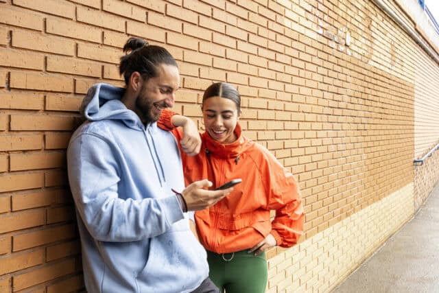 young couple looking at phone outdoors