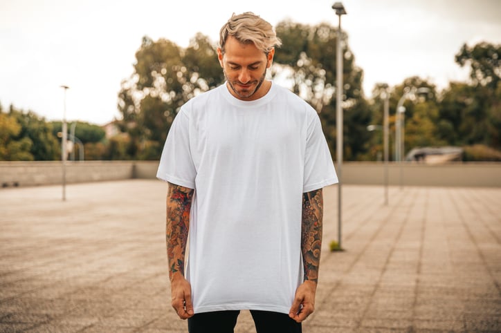 man with tattoos outdoors looking down