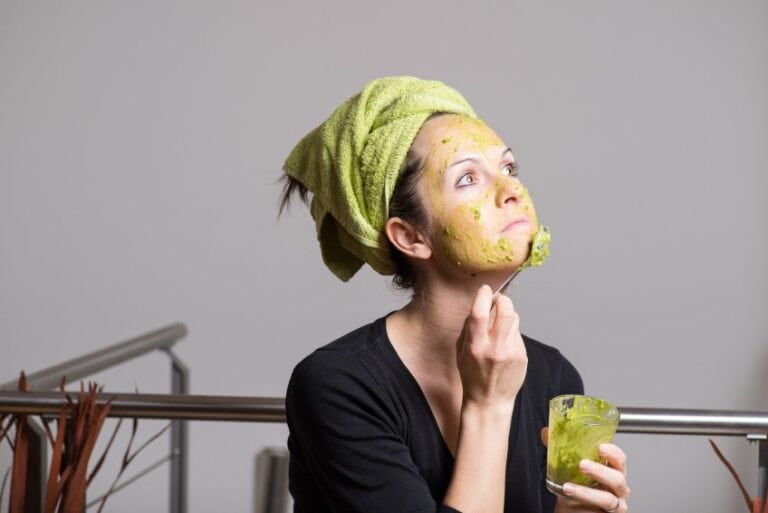 Woman applying avocado on face.