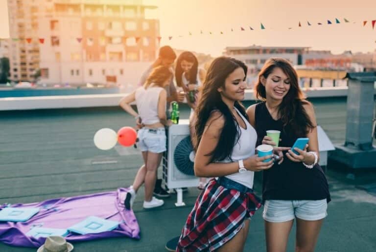 female friends reading texts at rooftop party