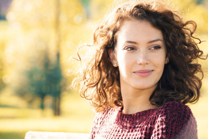 Young woman sitting on the bench at autumn