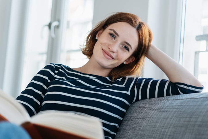 smiling redhead woman reading on couch
