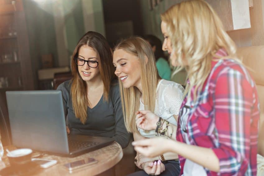 Three friends gathered round laptop