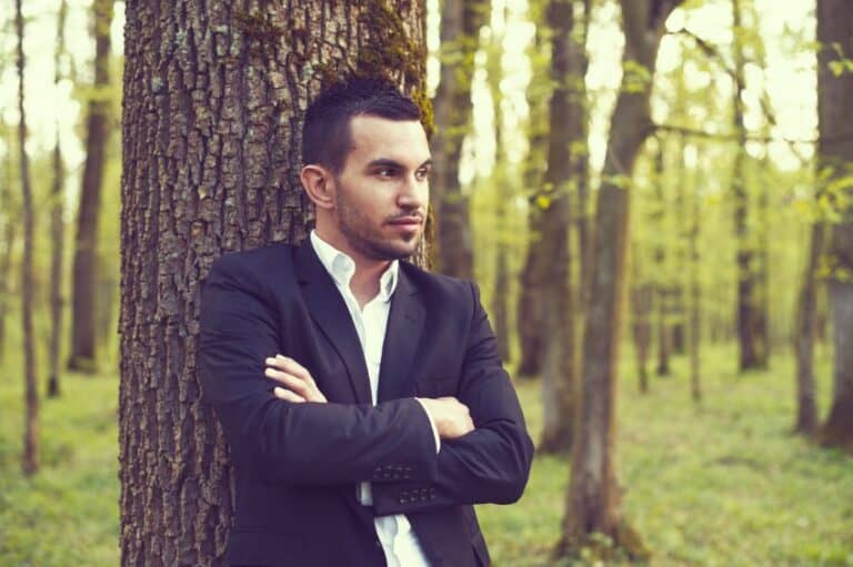 Young man leaning up a tree