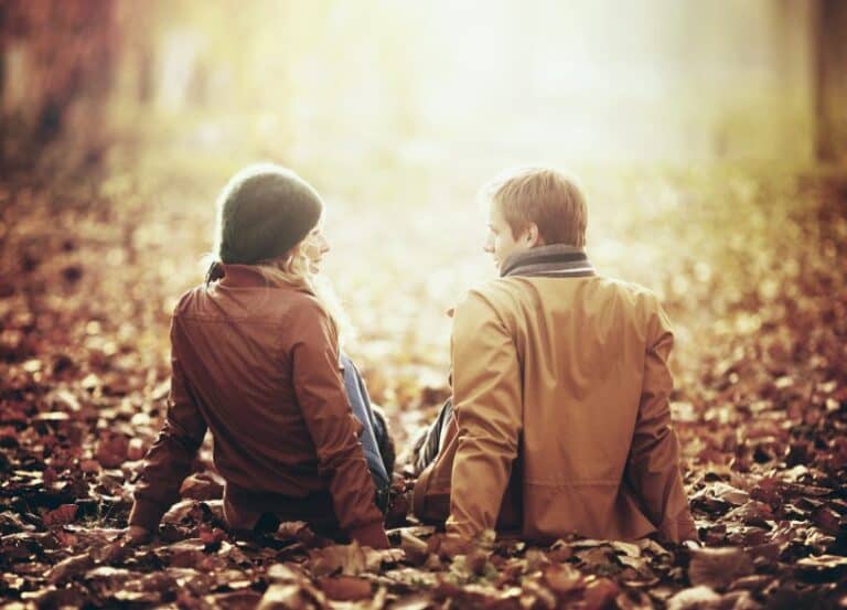Couple sat in leaves in park