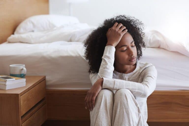 Afro American girl sat beside bed