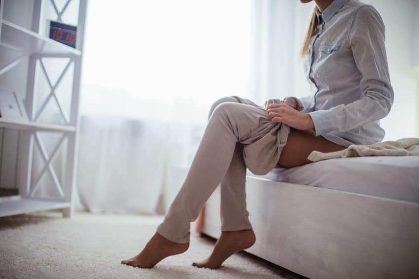 Woman sat in bedroom getting dressed