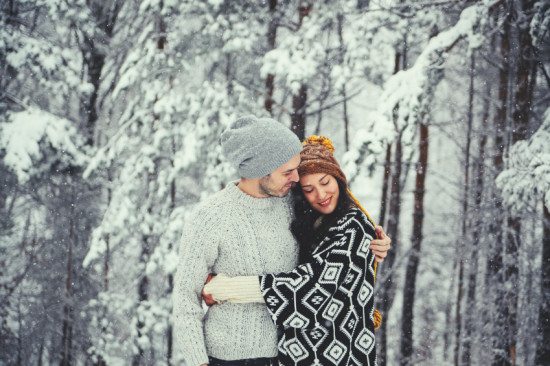Couple embracing in snowy winter forest.