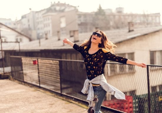 happy woman on rooftop with arms spread