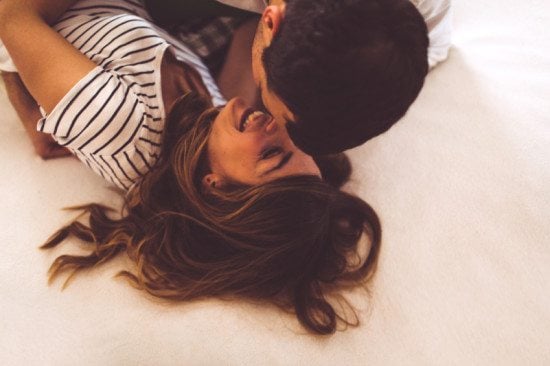 laughing couple kissing in bed