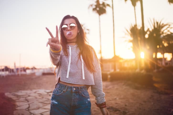 Hipster teen girl on island vacations blowing pink bubble gum