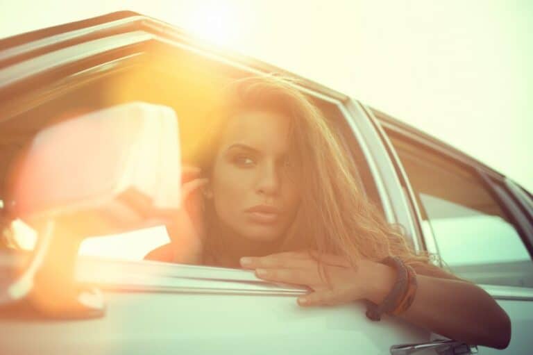 woman looking in car's rearview mirror