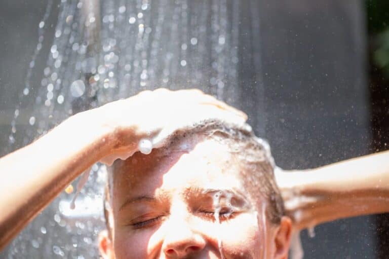 Woman washing hair in outdoor shower.