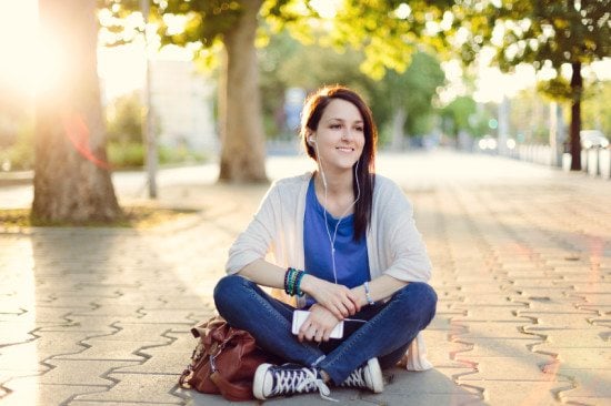 smiling woman with headphones on pavement