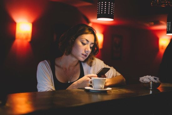 serious woman texting in dim cafe