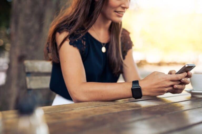 woman texting at cafe table outside