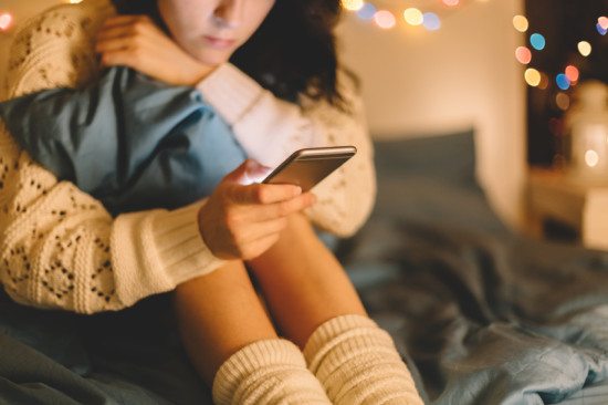 close-up of woman texting in bed