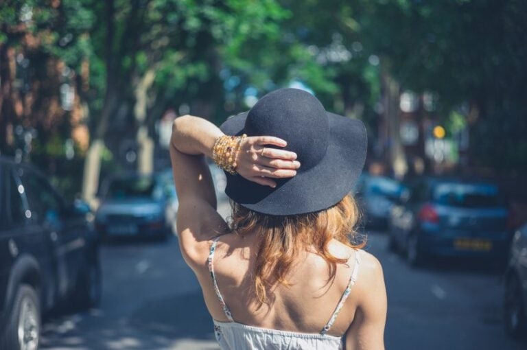 woman in hat walking city streets