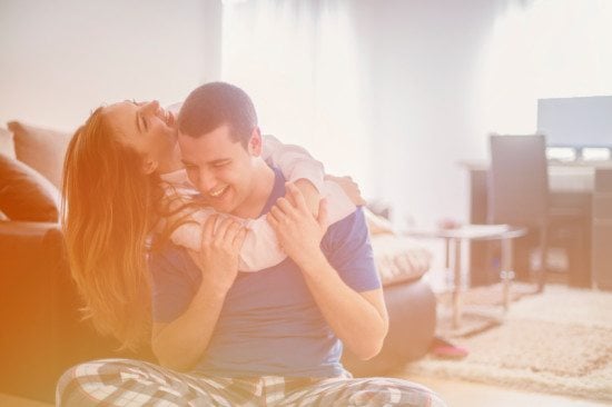 laughing couple cuddling at home
