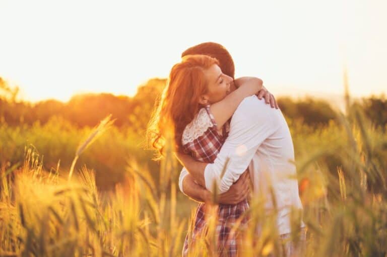 couple hugging field sunset