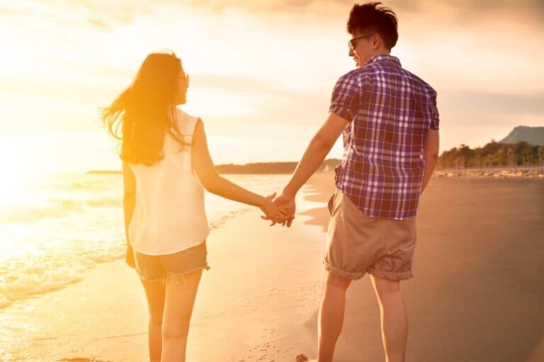 couple holding hands beach sunset