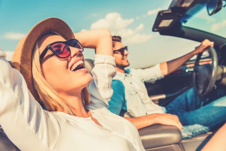 happy couple driving in convertible