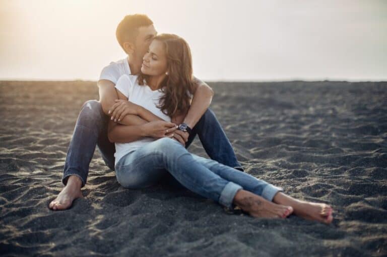 couple embracing sand beach sunset