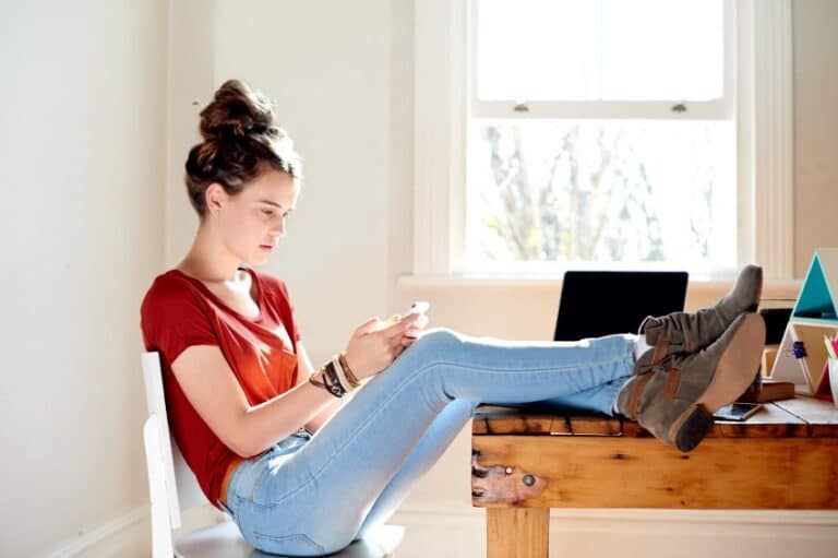 girl texting phone desk sun apartment