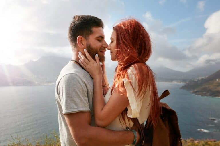 couple kissing mountain water