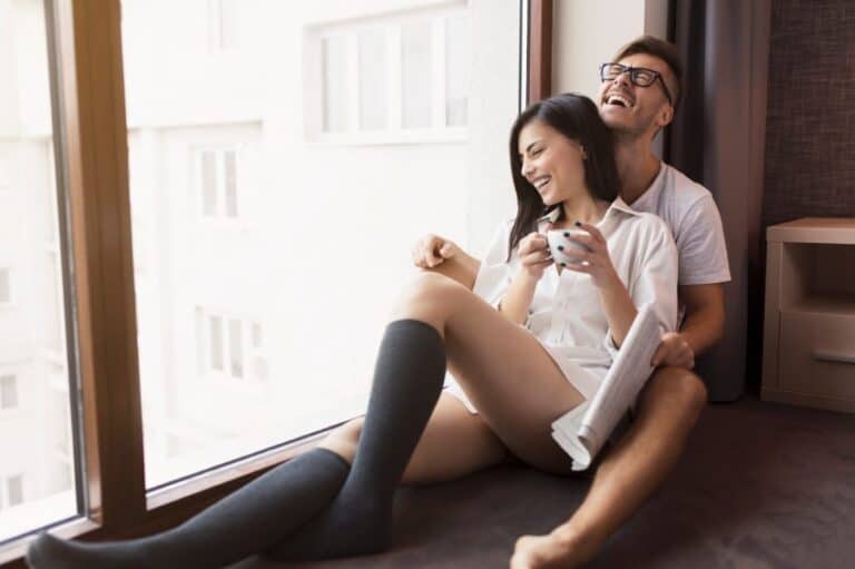 couple smiling cuddling window sill