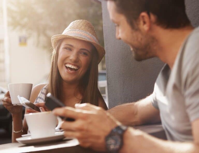 Couple sat with phones laughing