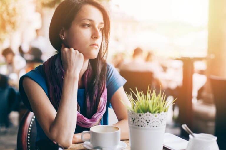 Girl sat drinking coffee at table