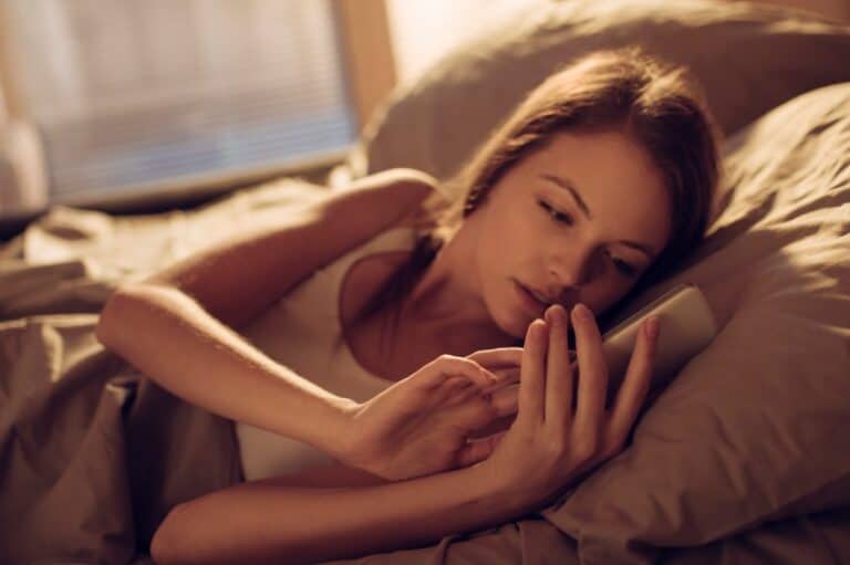 Brunette laid in bed texting