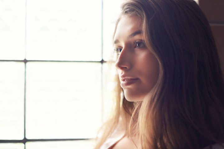 Young brunette thinking near window