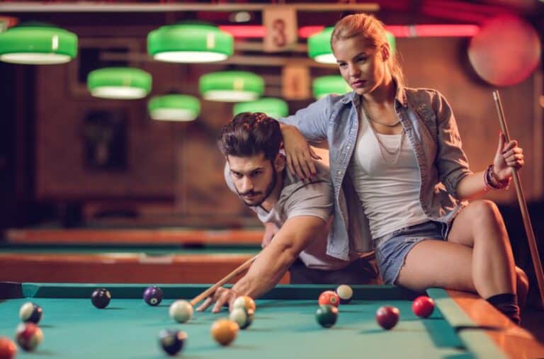 Young couple playing snooker in a pool hall.
