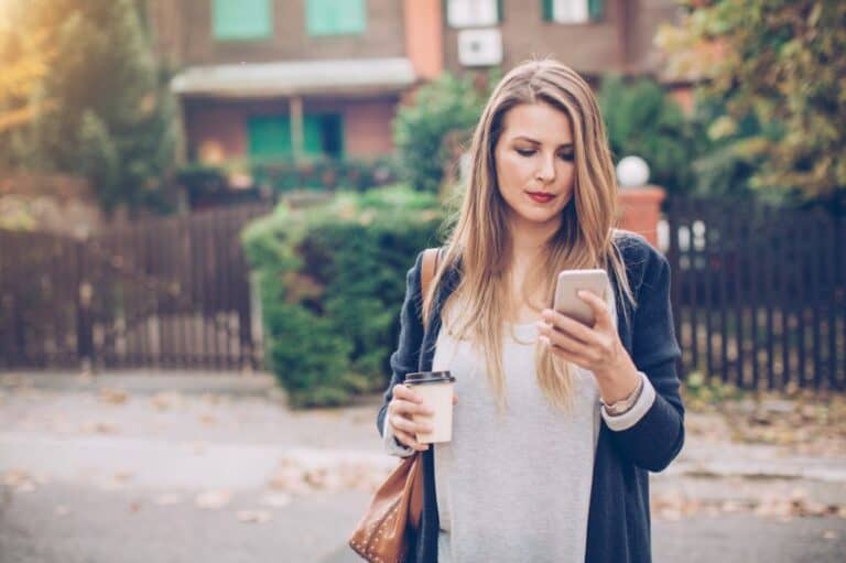 Woman carrying coffee and mobile