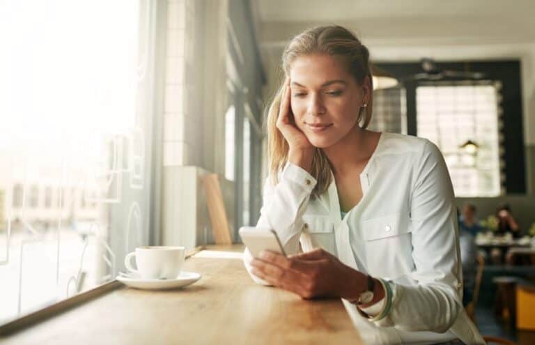 Blonde looking at mobile in coffee shop