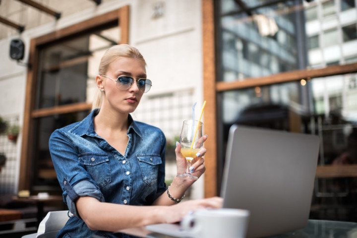 Blonde sat with laptop drinking