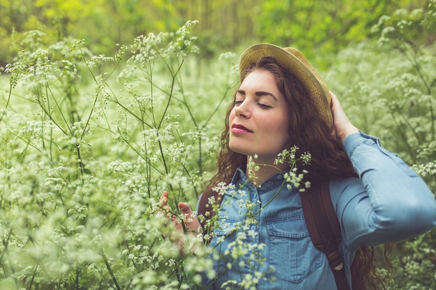 Beautiful caucasian girl in nature, enjoying the scents of wildflowers.