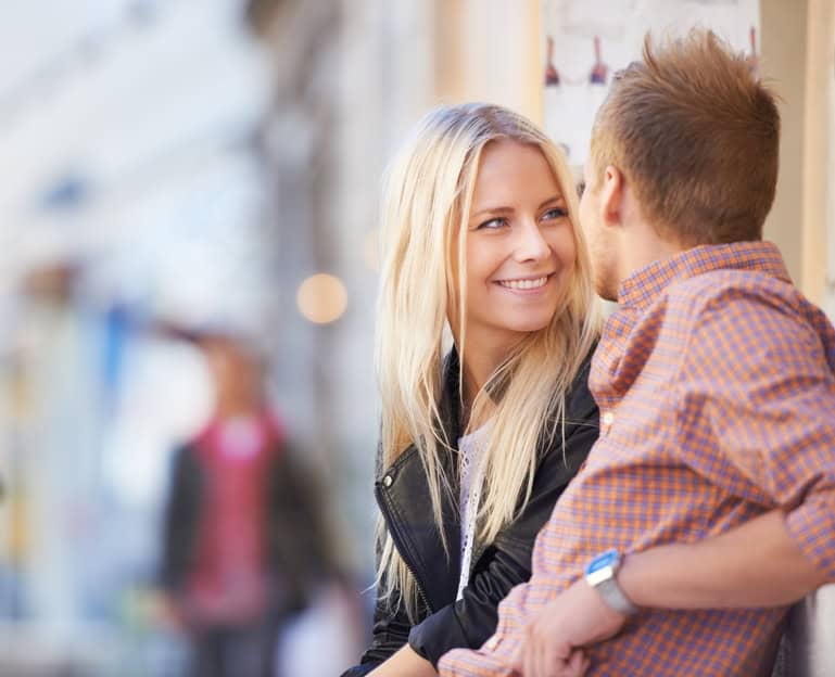 A young couple having a conversation on a bench in the street