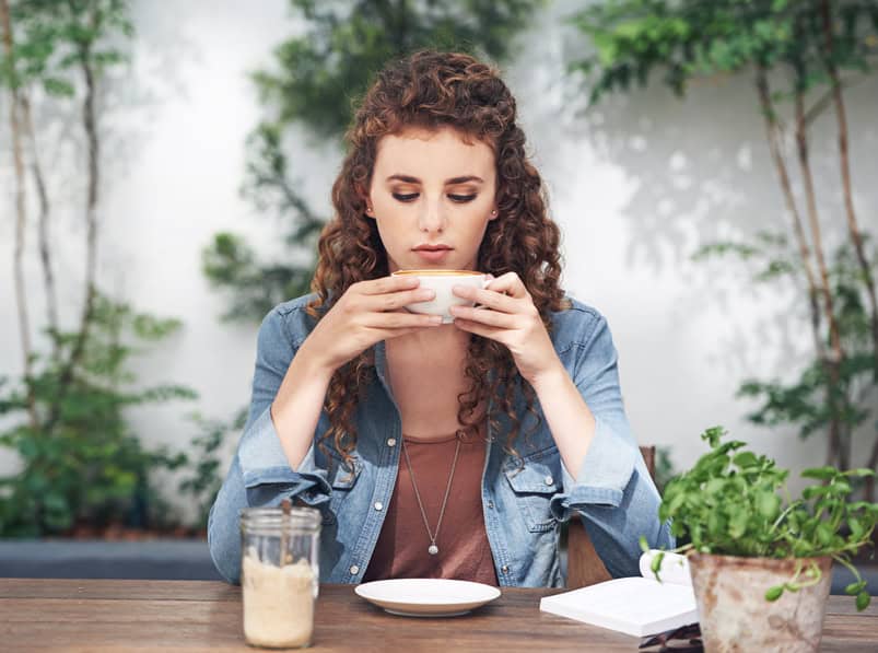 Young curly haired woman drinking coffee