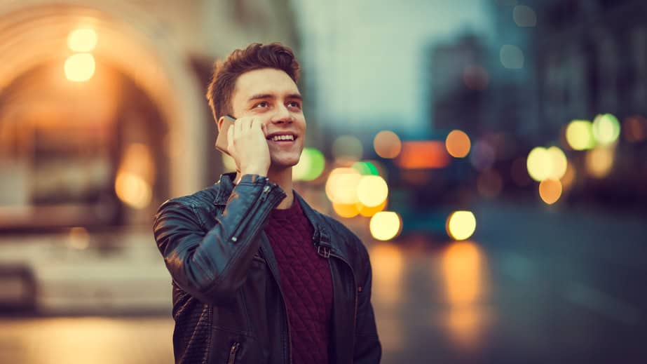 Young man talking on the phone outdoors at nighttime