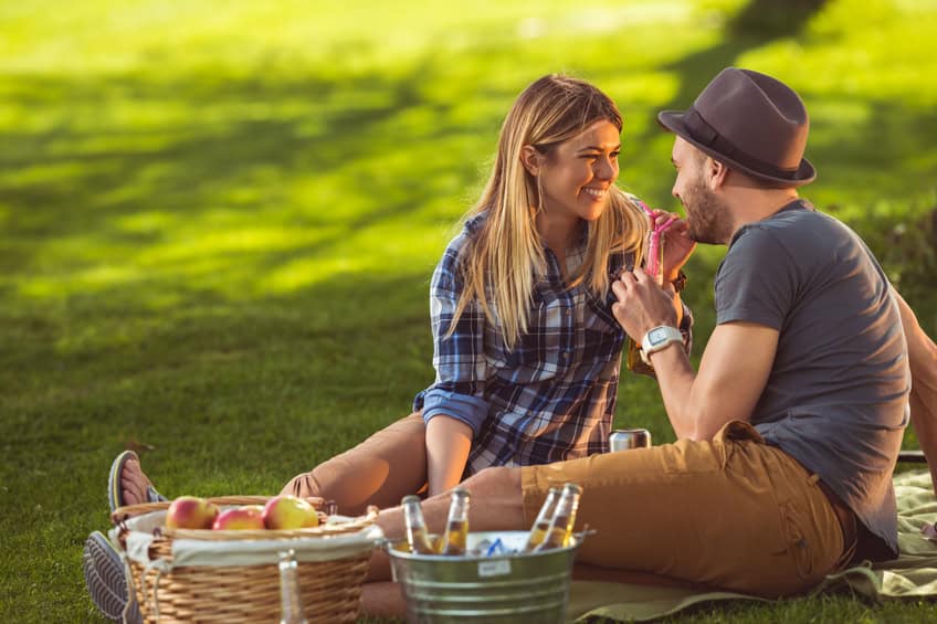 An affectionate couple enjoying a picnic outdoors.
