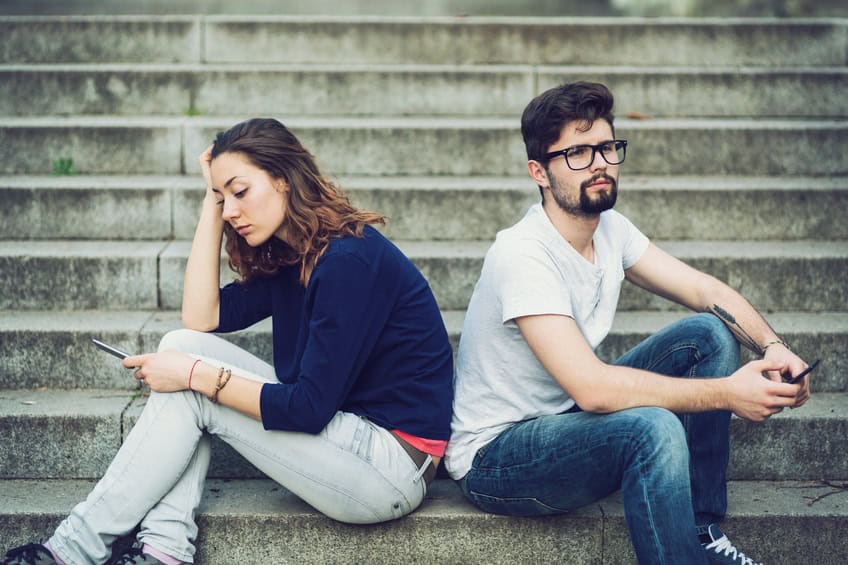 Couple ignoring each other while sitting on stairs back to back