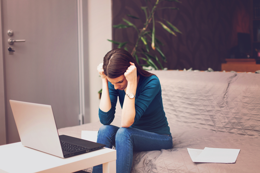 Woman sitting by a computer with bills, stressing out.