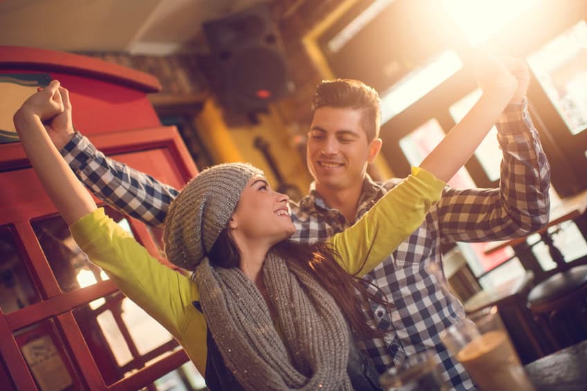 Happy young couple having good time together in a cafe. They are holding hands and looking at each other.
